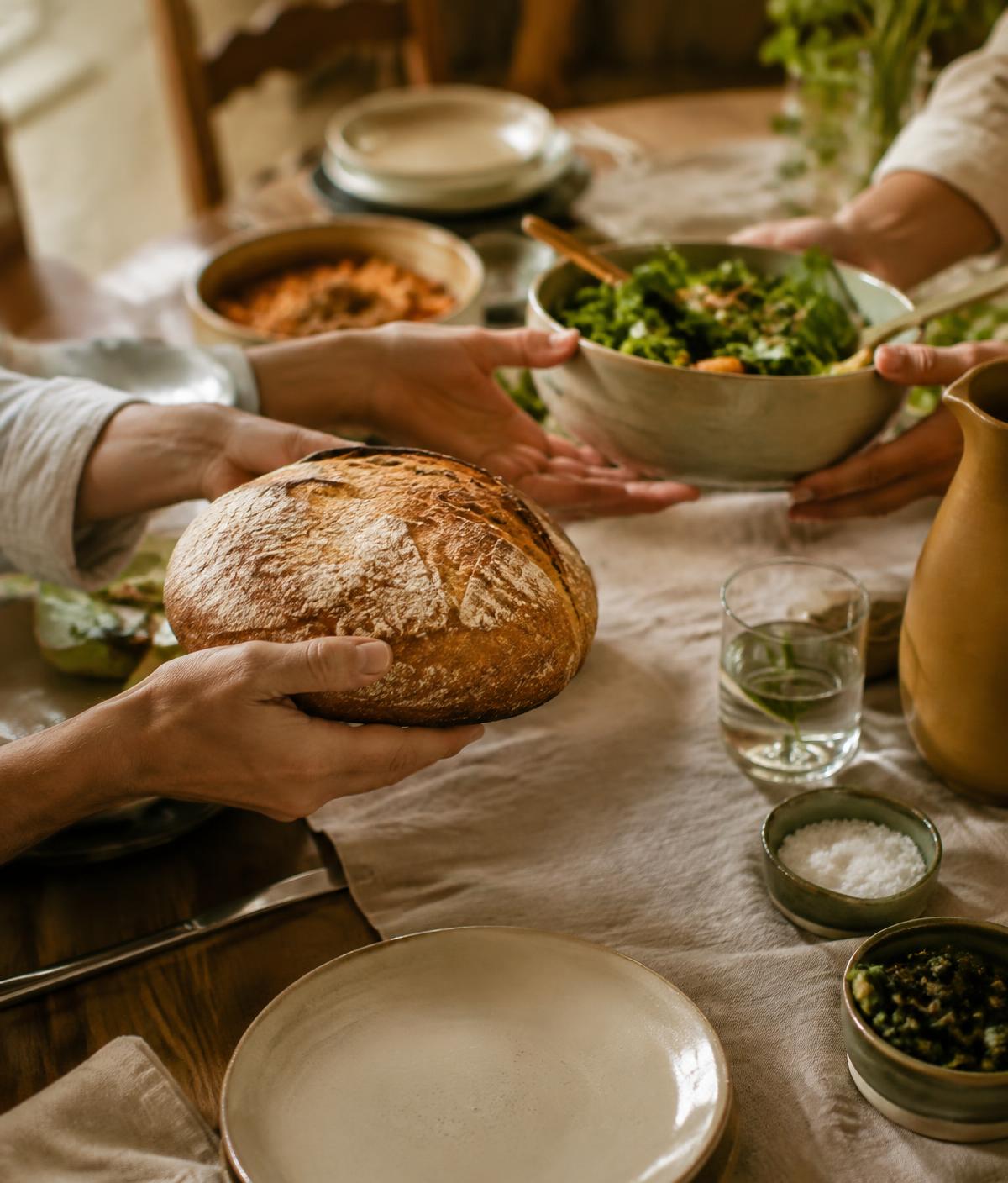 Bread and salad passed across a family table